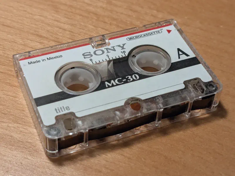 A sony microcasette tape on a table. It’s wound to the beginning.