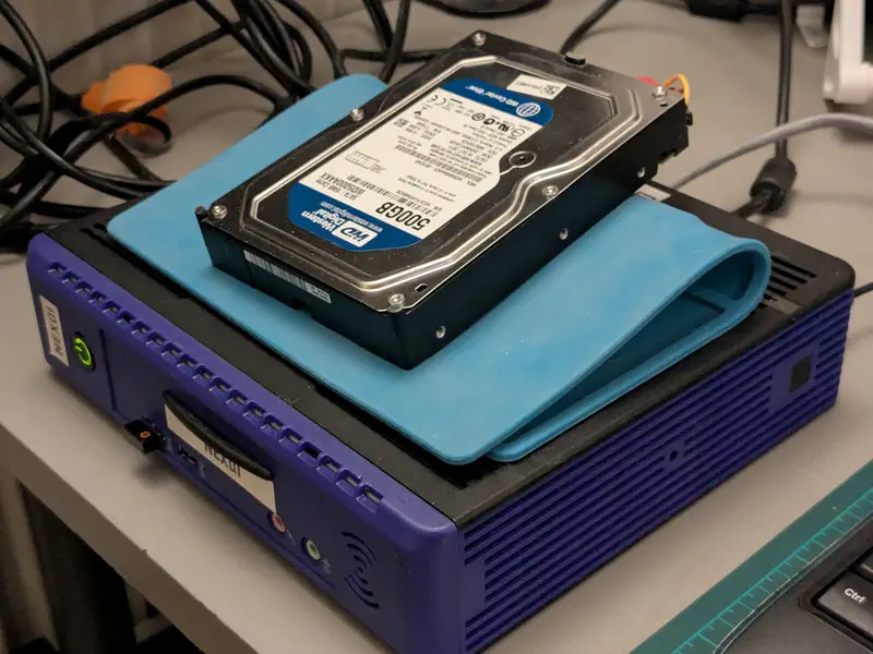An older harddisk haphazardly mounted on a modded 1L computer.